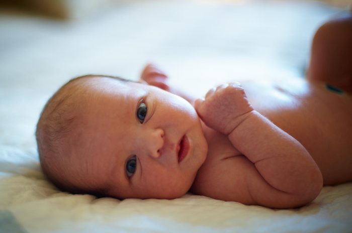 Cute newborn baby lying in bed at home